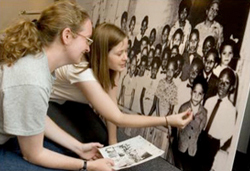 two people lean in towards an old black and white photo